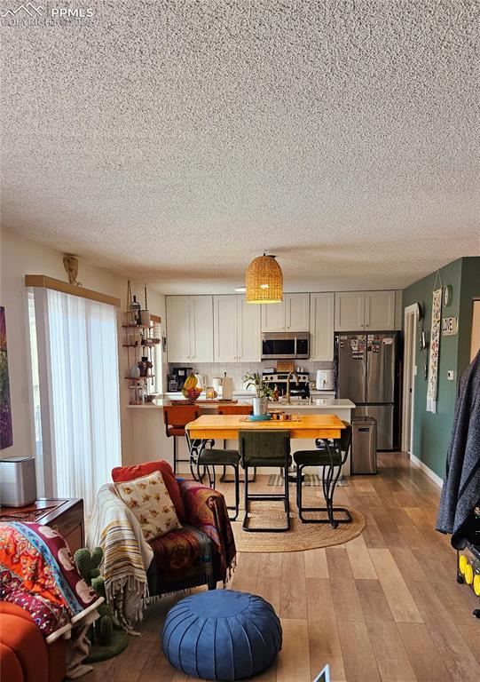 interior space with tasteful backsplash, stainless steel appliances, light hardwood / wood-style floors, and a textured ceiling