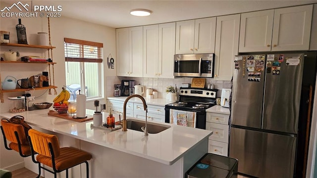 kitchen featuring sink, a breakfast bar area, white cabinets, kitchen peninsula, and stainless steel appliances