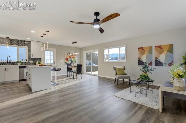 kitchen with light wood finished floors, a kitchen bar, stainless steel dishwasher, white cabinetry, and a sink