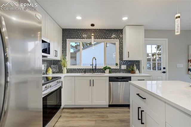 kitchen featuring a sink, decorative light fixtures, appliances with stainless steel finishes, white cabinets, and decorative backsplash