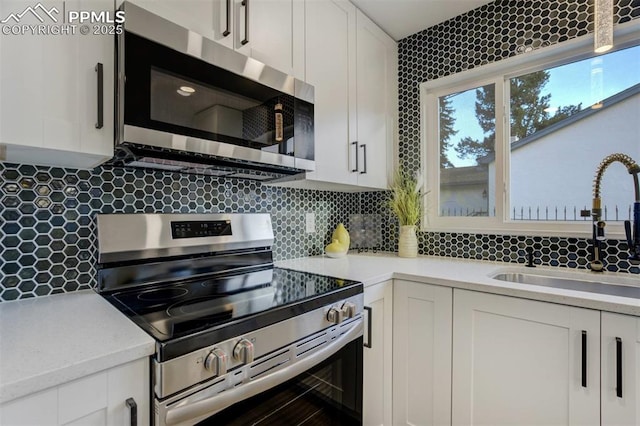 kitchen featuring a sink, stainless steel appliances, tasteful backsplash, and white cabinets