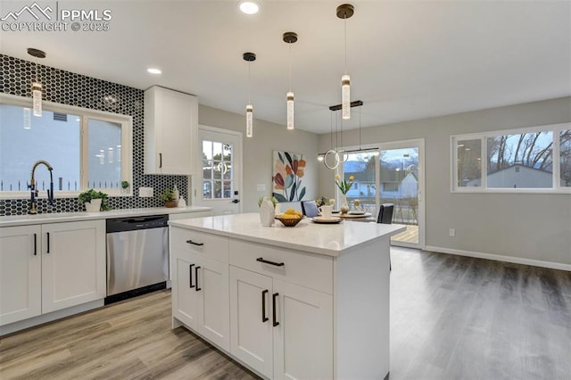 kitchen featuring hanging light fixtures, dishwasher, white cabinetry, and a sink