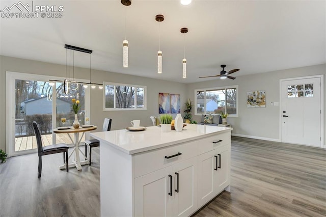 kitchen featuring light countertops, a kitchen island, light wood finished floors, and pendant lighting