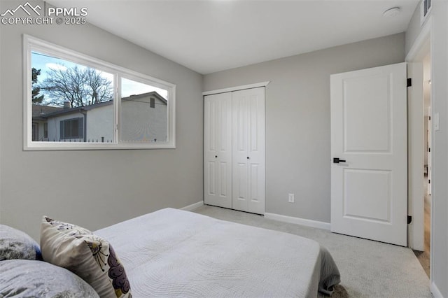 bedroom with light carpet, visible vents, a closet, and baseboards