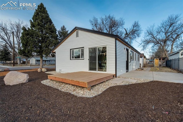 rear view of house with a wooden deck, a patio area, and fence