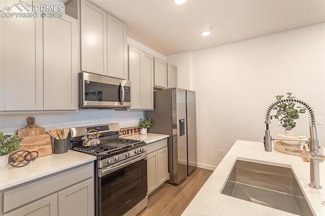 kitchen with stainless steel appliances, light hardwood / wood-style floors, and sink