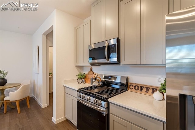 kitchen with appliances with stainless steel finishes and dark hardwood / wood-style floors