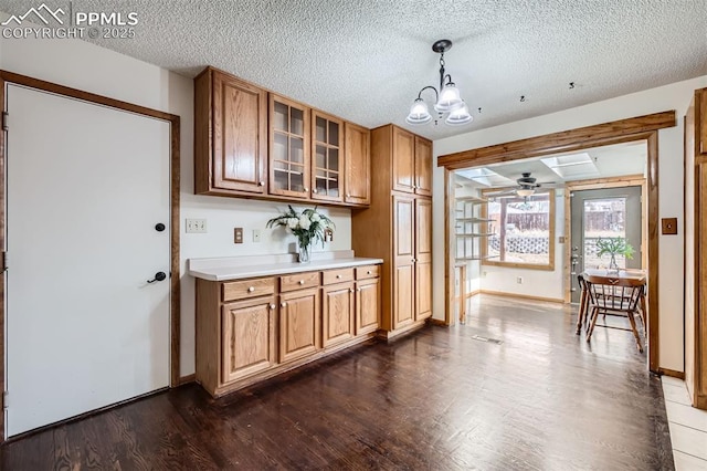 kitchen featuring pendant lighting, dark hardwood / wood-style flooring, ceiling fan with notable chandelier, and a textured ceiling