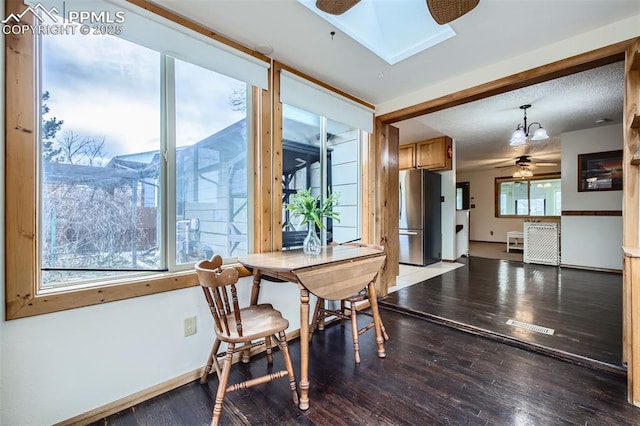 dining room with wood-type flooring, ceiling fan, and a skylight