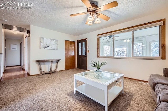 living room featuring ceiling fan, carpet flooring, and a textured ceiling