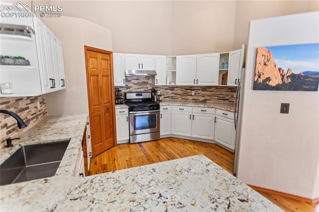 kitchen with sink, gas range, white cabinetry, light stone counters, and light hardwood / wood-style flooring