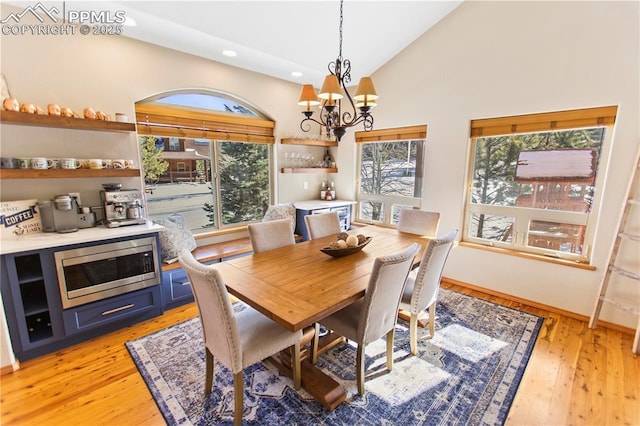 dining room featuring high vaulted ceiling, a chandelier, and light hardwood / wood-style floors