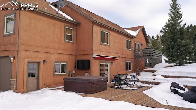 snow covered rear of property featuring a hot tub and a deck