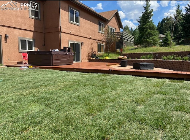 rear view of property with a hot tub, a wooden deck, and a yard