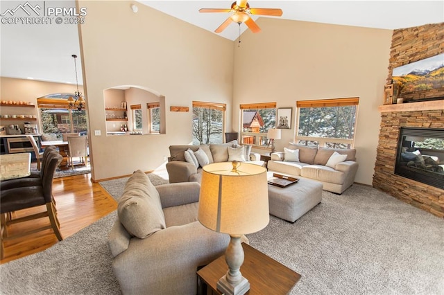 living room featuring ceiling fan, a stone fireplace, high vaulted ceiling, and a healthy amount of sunlight