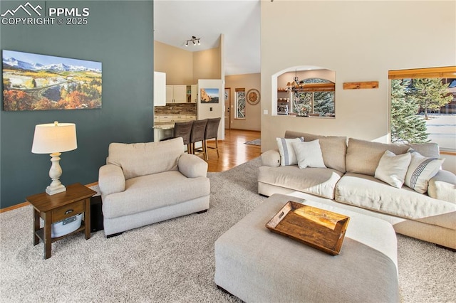 living room with high vaulted ceiling and light wood-type flooring