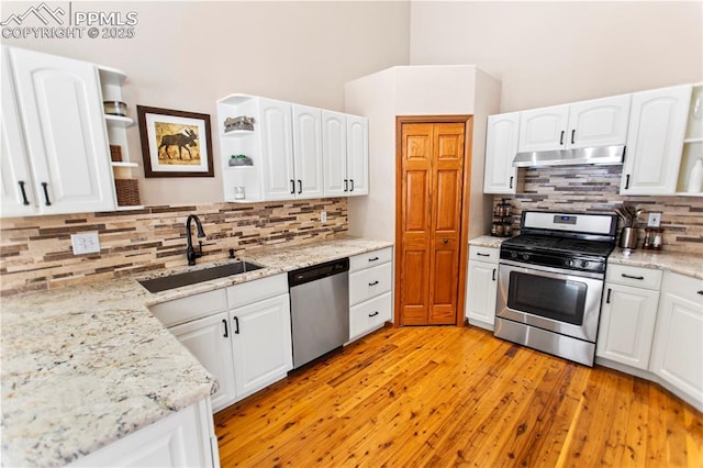 kitchen with sink, appliances with stainless steel finishes, light stone countertops, light hardwood / wood-style floors, and white cabinets