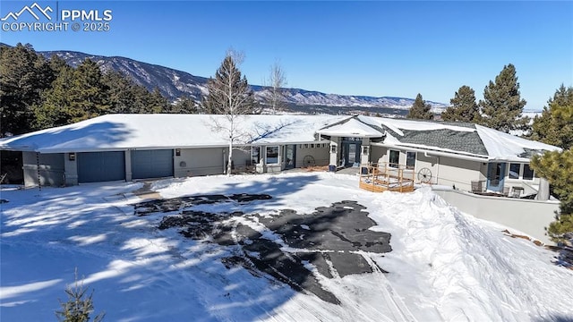 snow covered property featuring a garage and a mountain view