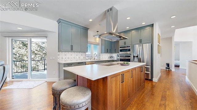 kitchen with a kitchen island, island range hood, tasteful backsplash, sink, and stainless steel appliances