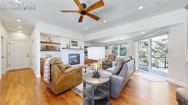 living room featuring built in shelves, ceiling fan, and light hardwood / wood-style flooring