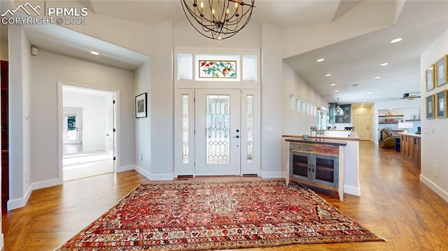 entryway with an inviting chandelier, light hardwood / wood-style flooring, and a high ceiling