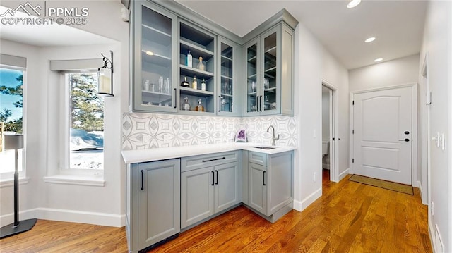 bar with sink, gray cabinets, and wood-type flooring