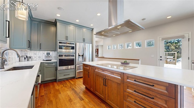 kitchen featuring tasteful backsplash, sink, hanging light fixtures, island exhaust hood, and stainless steel appliances