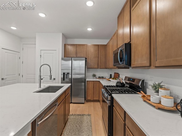 kitchen featuring light stone countertops, appliances with stainless steel finishes, sink, and light hardwood / wood-style floors