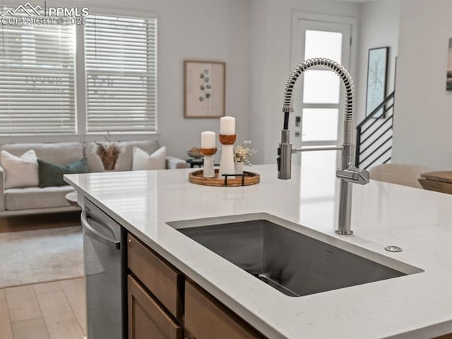 kitchen with dishwasher, sink, and light wood-type flooring