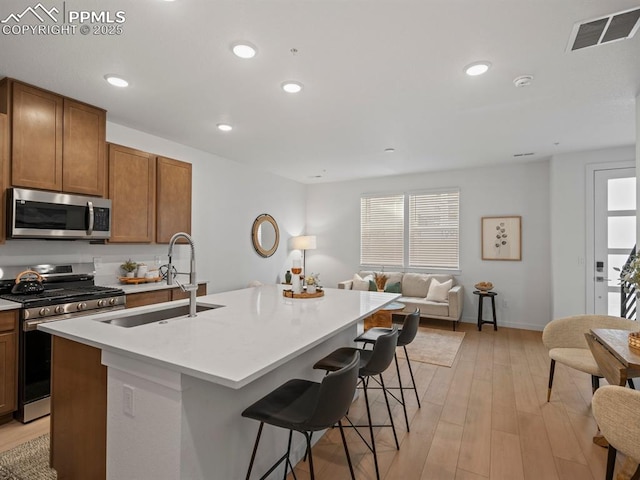 kitchen featuring sink, a kitchen bar, an island with sink, and appliances with stainless steel finishes