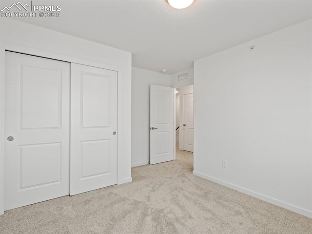 unfurnished bedroom with light carpet and a closet