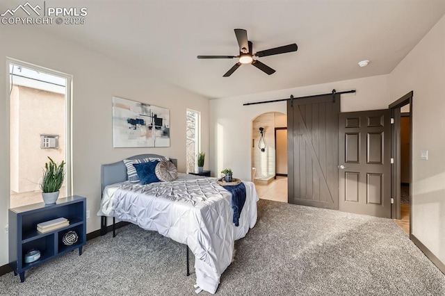 bedroom with a barn door, ceiling fan, and carpet flooring