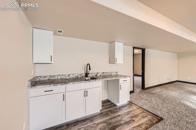 kitchen with sink, dark hardwood / wood-style floors, white cabinets, and stone counters