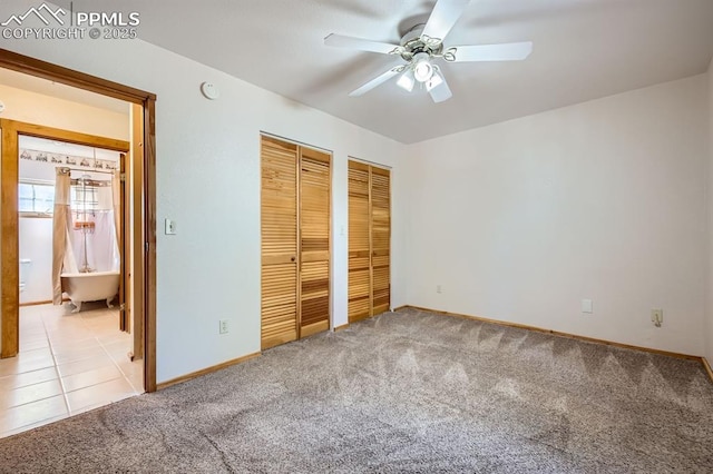 unfurnished bedroom with ceiling fan, ensuite bathroom, light carpet, and two closets