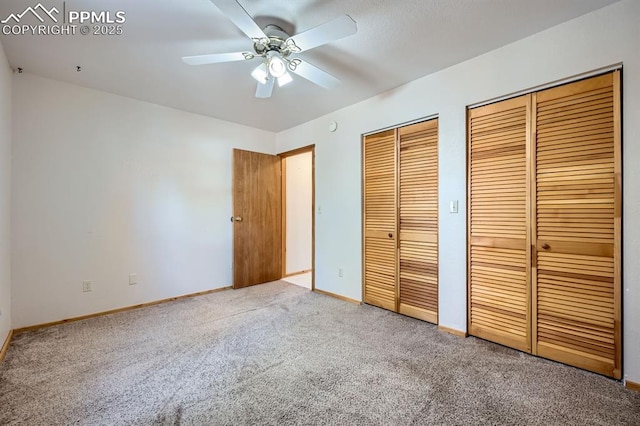 unfurnished bedroom featuring ceiling fan, multiple closets, and carpet