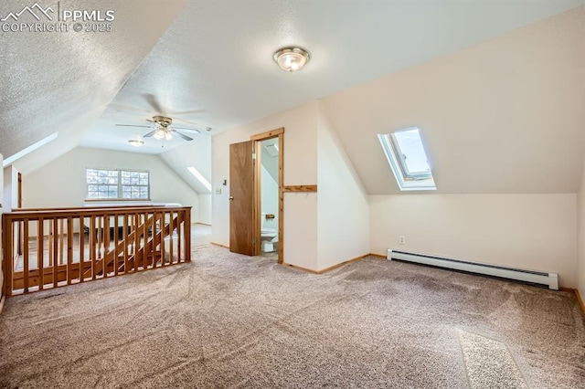 bonus room featuring lofted ceiling with skylight, carpet, a baseboard heating unit, and a textured ceiling