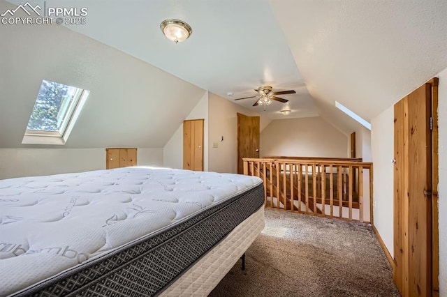 carpeted bedroom with vaulted ceiling with skylight and ceiling fan