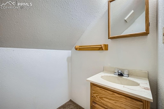 bathroom featuring vanity, vaulted ceiling, and a textured ceiling