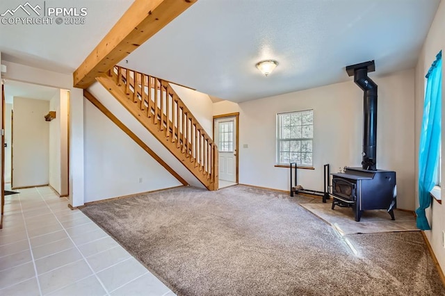 entrance foyer with beamed ceiling, carpet floors, and a wood stove