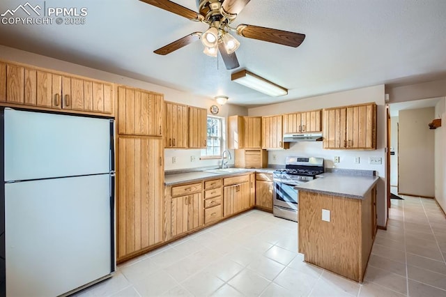 kitchen with sink, ceiling fan, white refrigerator, stainless steel range with gas cooktop, and light brown cabinets