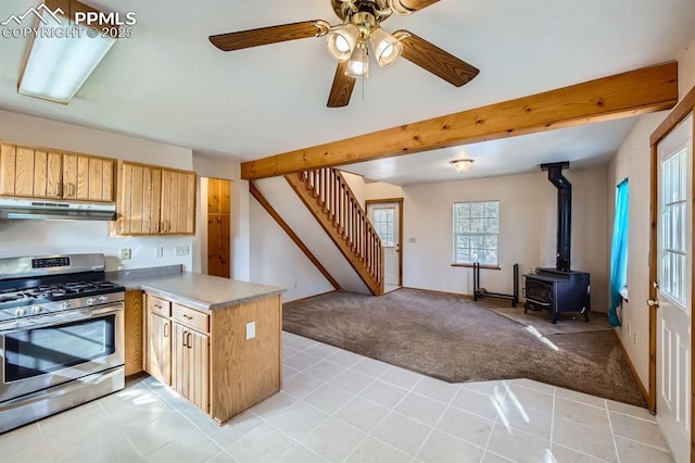 kitchen featuring light carpet, beam ceiling, gas stove, and kitchen peninsula