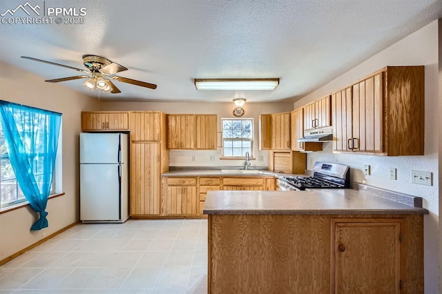 kitchen with sink, a textured ceiling, fridge, stainless steel stove, and ceiling fan