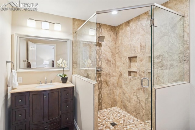 bathroom featuring a shower with door and vanity