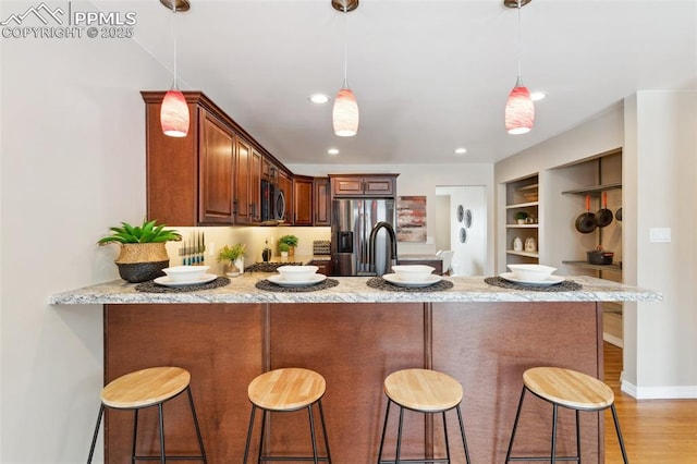 kitchen with stainless steel appliances, kitchen peninsula, hanging light fixtures, and a breakfast bar area