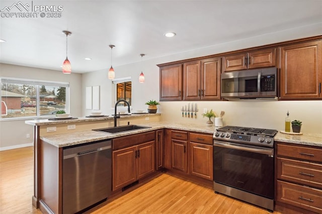 kitchen featuring decorative light fixtures, appliances with stainless steel finishes, sink, and kitchen peninsula