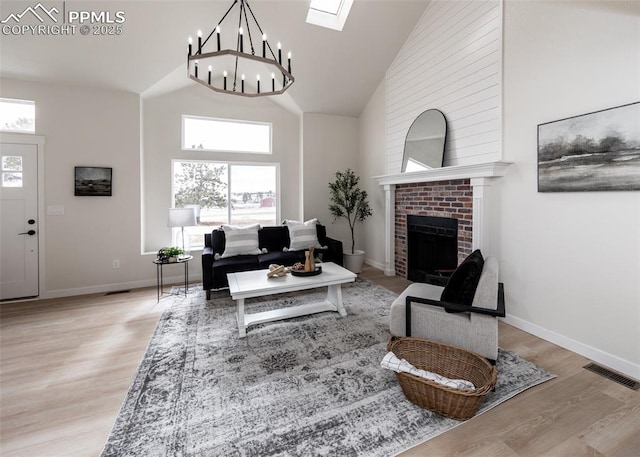 living room with a brick fireplace, high vaulted ceiling, light hardwood / wood-style floors, and a healthy amount of sunlight