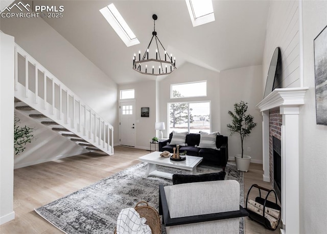 living room featuring a brick fireplace, a skylight, high vaulted ceiling, and light wood-type flooring