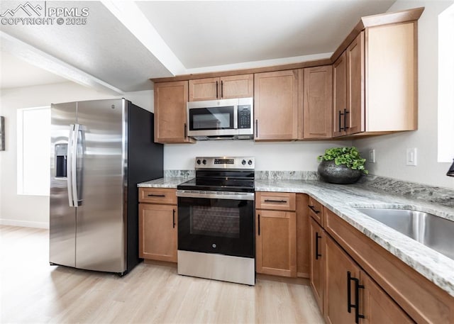 kitchen featuring sink, appliances with stainless steel finishes, beam ceiling, light stone countertops, and light hardwood / wood-style floors