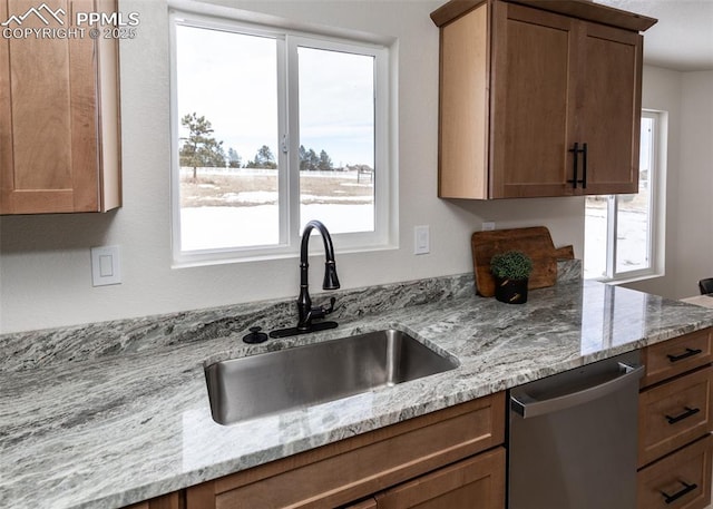 kitchen featuring dishwasher, light stone countertops, sink, and a healthy amount of sunlight