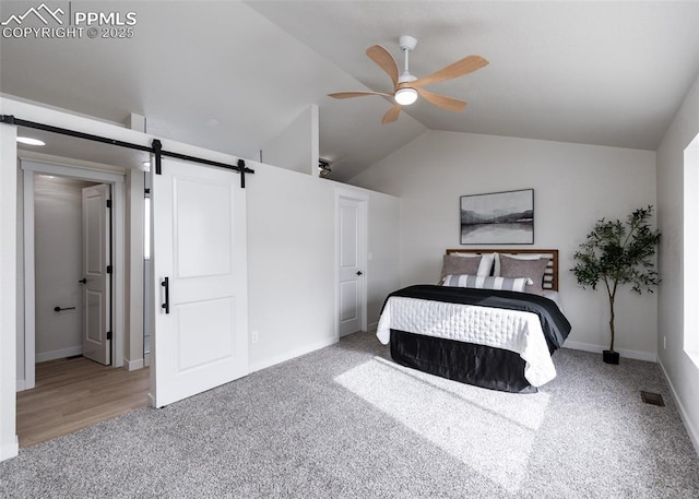 carpeted bedroom with vaulted ceiling, a barn door, and ceiling fan